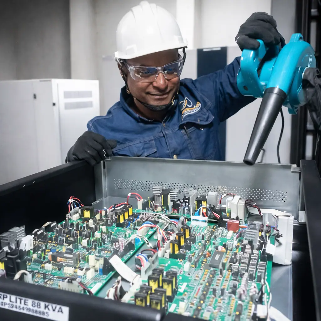 Técnico realizando la limpieza con aire comprimido de las tarjetas electrónicas internas de un sistema UPS